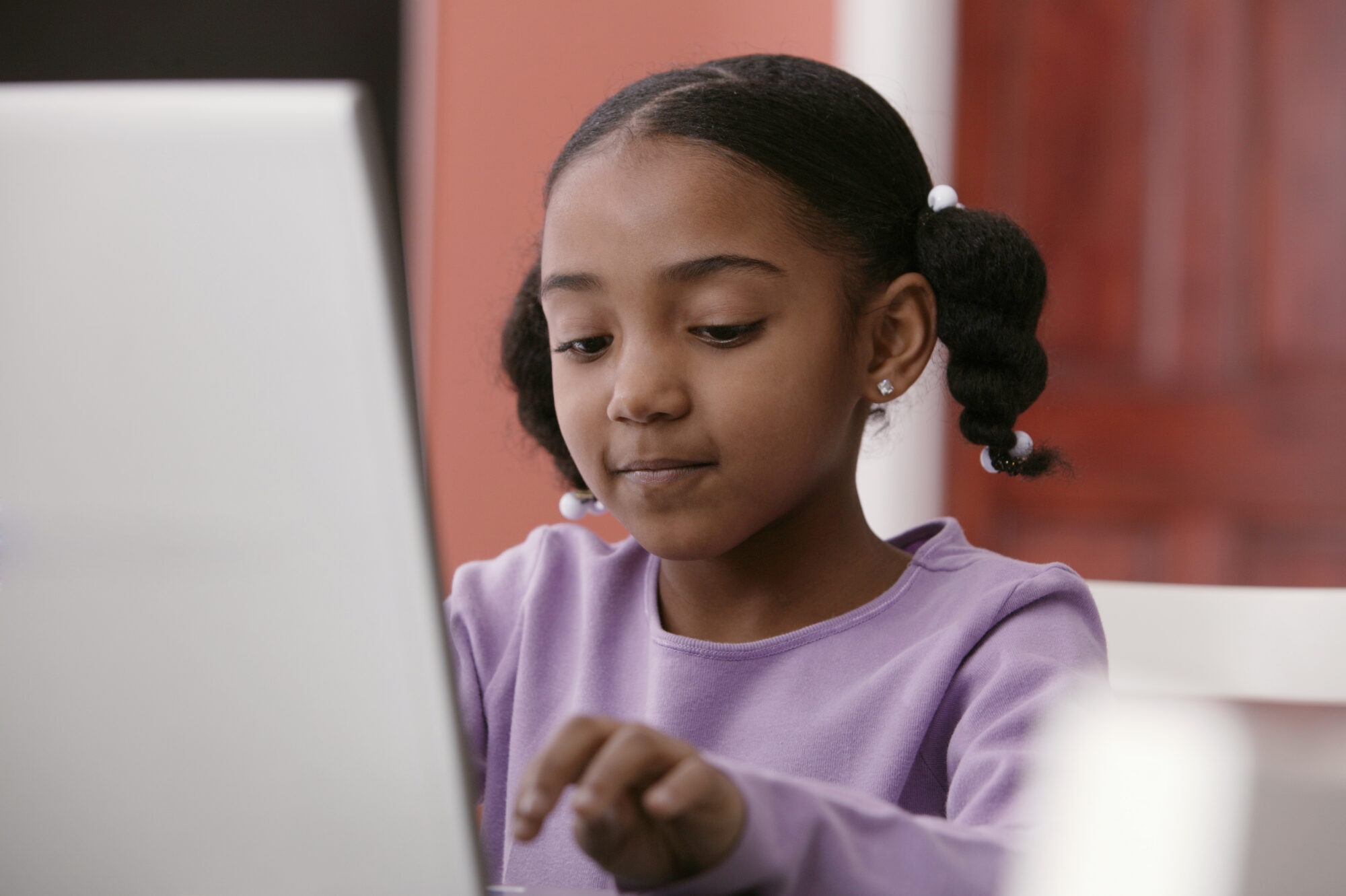 A young girl pupil uses a laptop at her desk