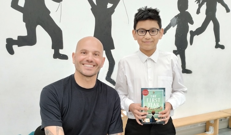Author sat next to pupil holding a book